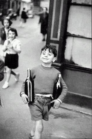 Мальчик несёт две бутылки алкоголя и улыбается